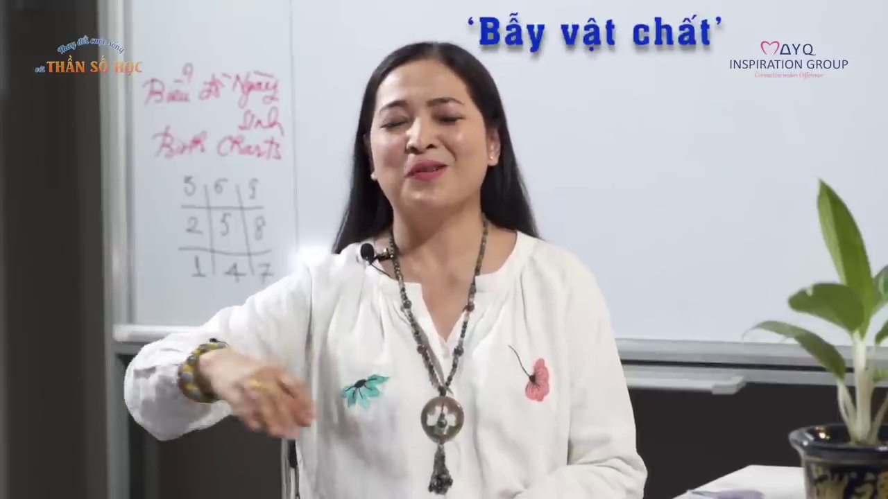 Chuyên gia dùng bút màu hồng chỉ vào các công thức và ví dụ ngày sinh cụ thể trên bảng để minh họa cách tính và ý nghĩa của số 11.