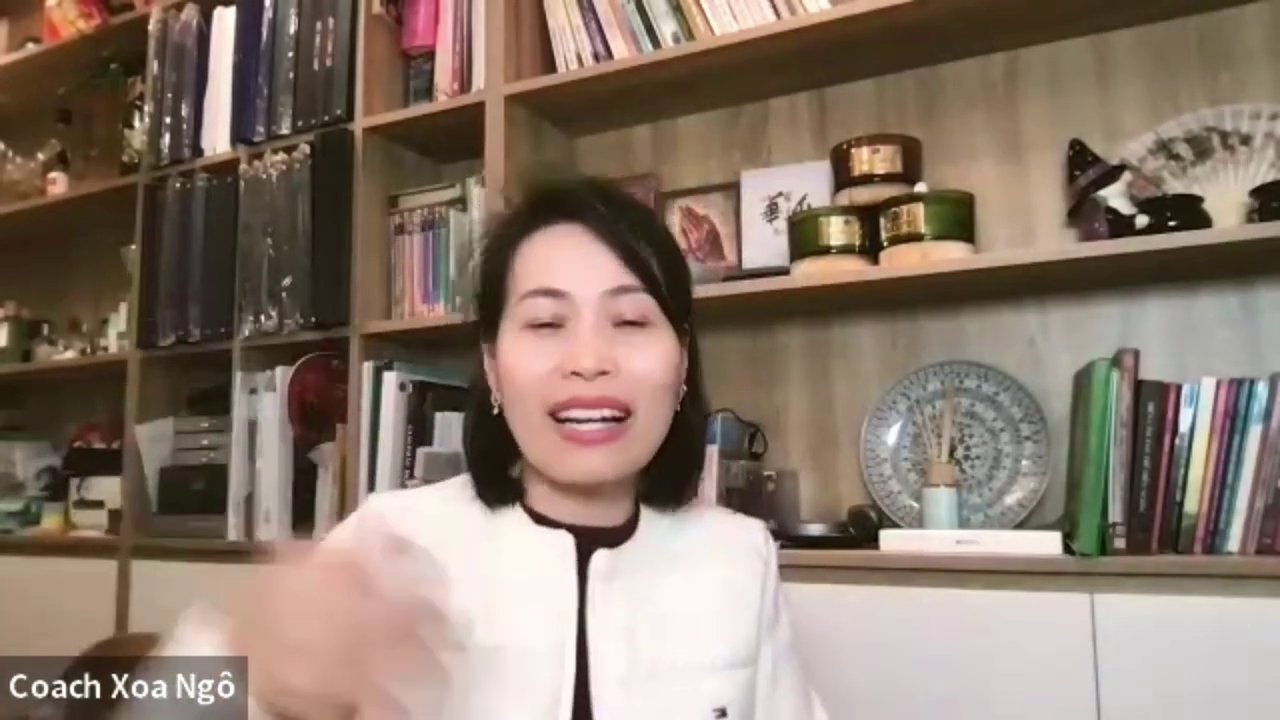 Một người đang đứng trên sân khấu, tay cầm micro, tự tin trình bày trước đám đông.